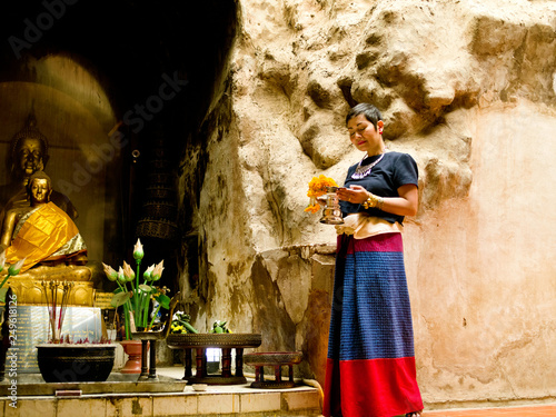 Femme thaïe en habit traditionnels faisant une offrande au boudha dans le temple souterrain du Wat Umong