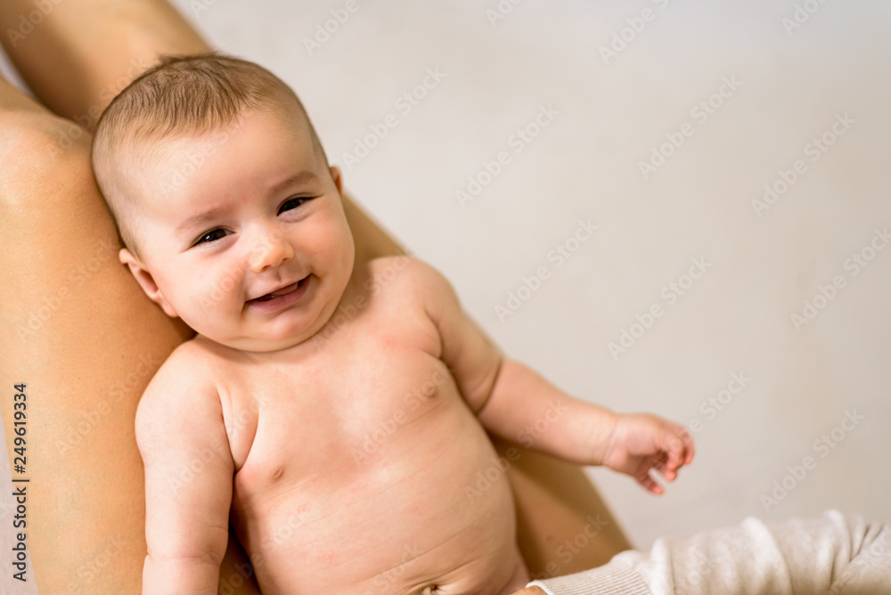 Newborn baby girl posed smiling casual way over her mother, looking at camera Newborn baby girl posed smiling casual way over her mother, looking at camera