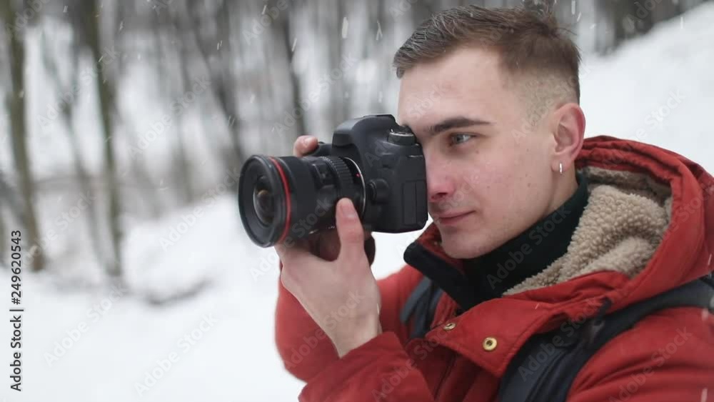 Young male photographer taking photo with camera in forest Young male photographer taking photo with camera in forest