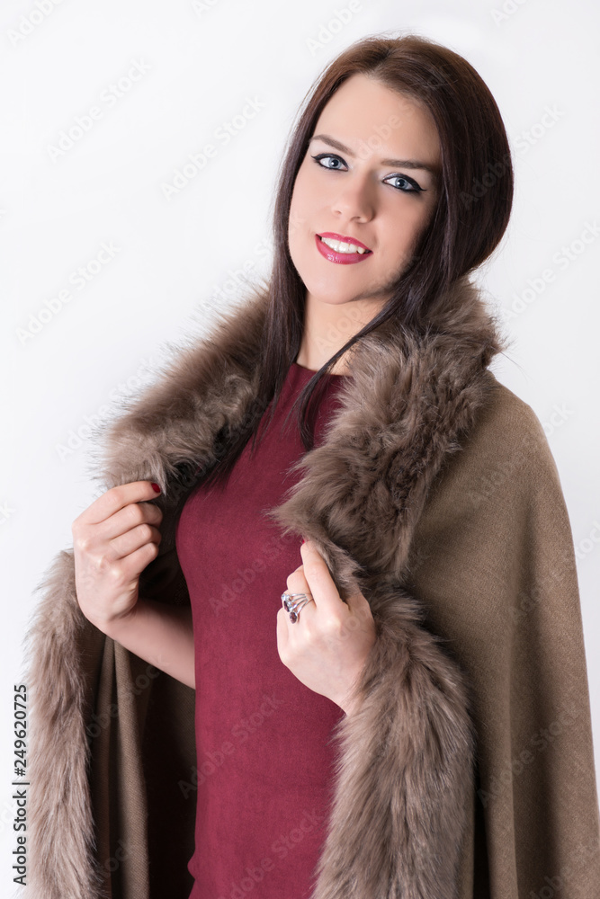 Gorgeous long haired girl in eco fur coat isolated on white background with happy smile. Laughing female model in elegant brown eco fur coat posing in studio. Close up