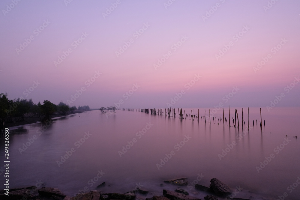 Fototapeta premium Wooden piles row in the sea in sunrise time.