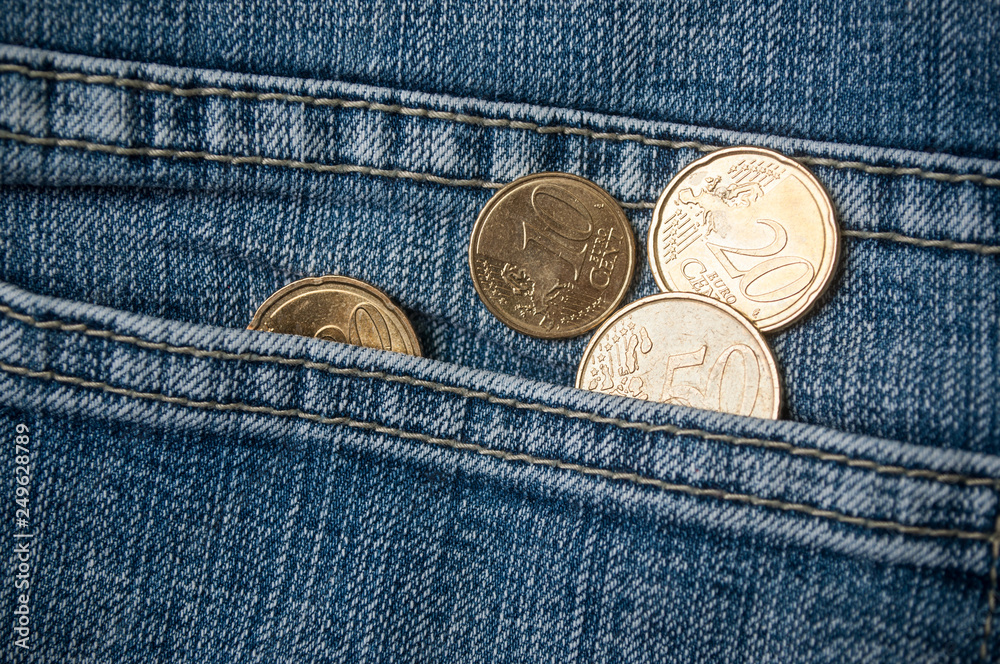 closeup of euros coins in blue jeans pocket