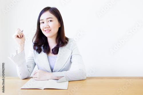 Portrait of Asian business women sitting on the wooden table in the office. © DG PhotoStock