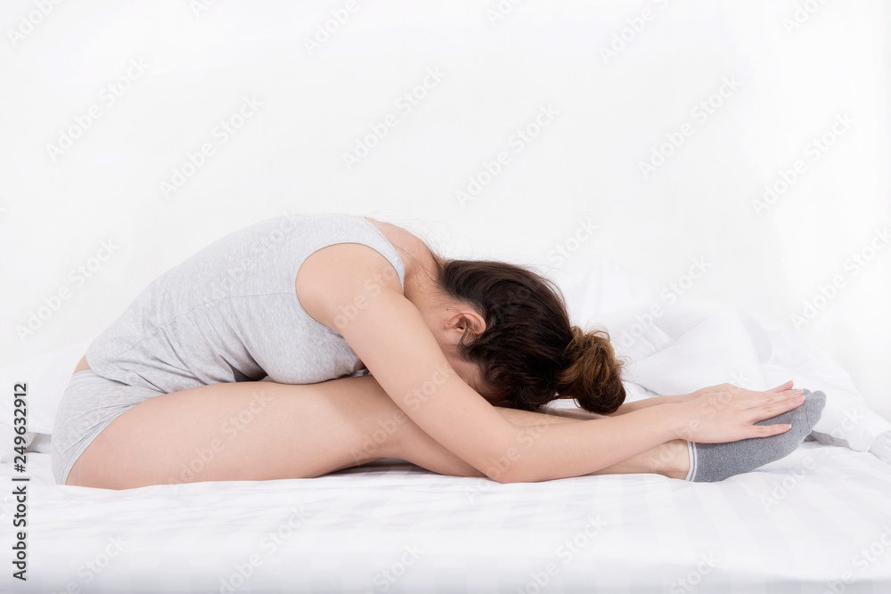 Attractive shape sporty woman doing seated yoga poses on the bed before sleeping. Attractive shape sporty woman doing seated yoga poses on the bed before sleeping.