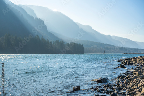 Mountain ridge illuminated by the slanting rays of the sun on the stony bank of the Columbia River in Colombia Gorge