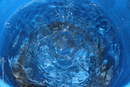 It is raining. Water flows into the blue bucket.