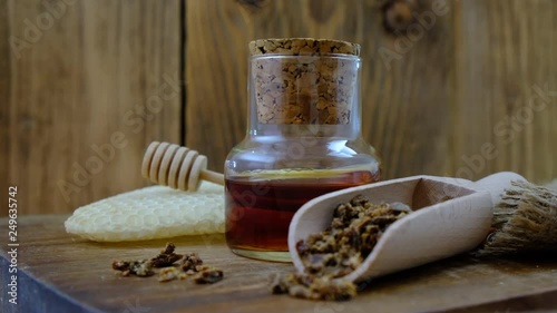 A bottle of propolis tincture and a wooden scoop of propolis granules. Medical preparations bee propolis. Bee glue. Apitherapy. How to treat bee products.