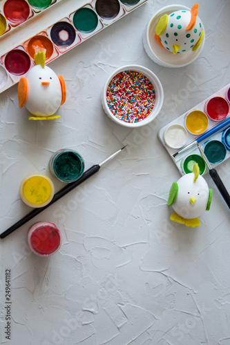 Preparation for Easter. Multi-colored paint, hands in the frame paint the eggs. handmade chickens and Bunny from the egg