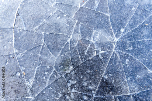 thin layer of ice on the pond surface with cracks texture background