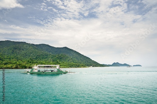 Landscape with turquoise tropical sea, cargo ferry and tropical Koh Chang island on horizon in Thailand