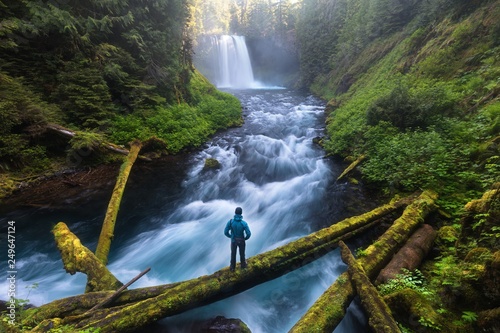 Man standing by a Koosah Falls, also known as Middle Falls, is second of the three major waterfalls of the McKenzie River, in the heart of the Willamette National Forest, in the U.S. state of Oregon.