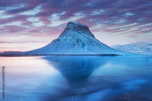Icelands snaefellsnes peninsula and famous Kirkjufell. Kirkjufell is a beautifully shaped and a symmetric, free standing mountain in Iceland. Frozen view of Kirkjufell (church mountain).
