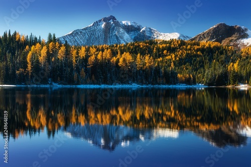 Beautiful reflection on a mountain lake. Wonderful autumn colors in the alps and yellow larch trees. Amazing landscape background concept