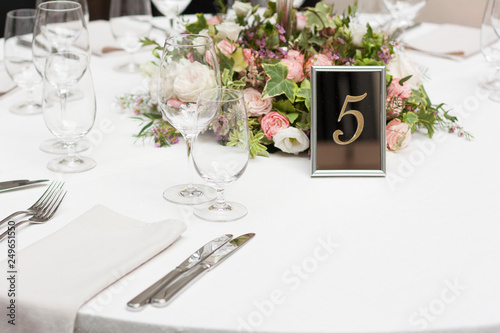 Beautiful flowers on the table.The restaurant is decorated with flowers on the wedding day. Candelabra with candles on the table. Number five.