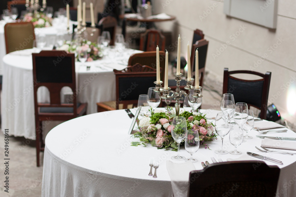 The restaurant is decorated with flowers on the wedding day. Candelabra with candles on the table The restaurant is decorated with flowers on the wedding day. Candelabra with candles on the table