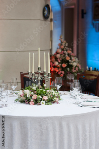 The restaurant is decorated with flowers on the wedding day. Candelabra with candles on the table. © klevers