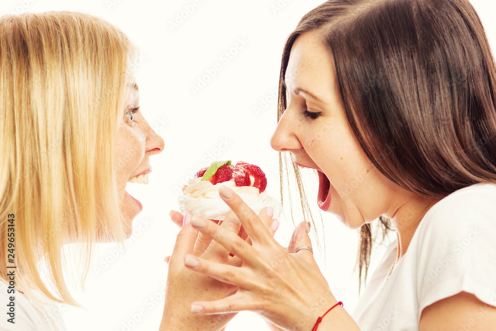 Young women eating cake, close-up, white background Young women eating cake, close-up, white background