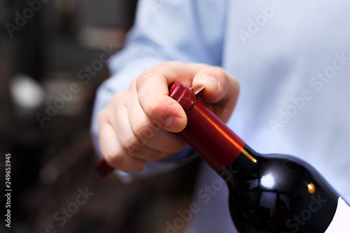 sommelier is opening a bottle of wine with a corkscrew
