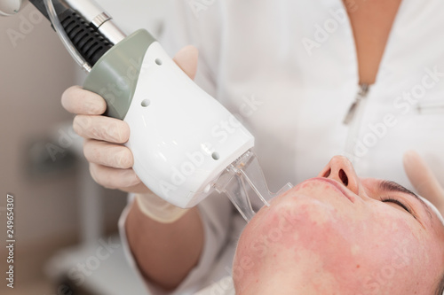 Laser rejuvenating facial face treatment at cosmetology clinic. Young woman getting lifting anti-aging and skincare, laser polishing facial therapy, aesthetic cosmetology. photo