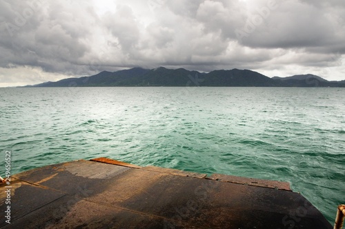 Ferry ramp, tropical sea, monsoon storm heavy clouds and tropical Koh Chang island on horizon in Thailand