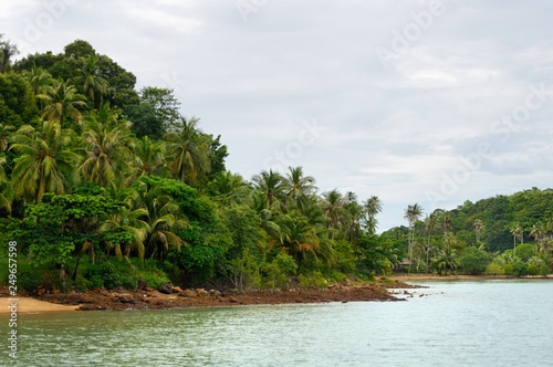 Tropical amber sand beach, rocks, coconut palm trees and turquoise tropical sea on Koh Chang Island in Thailand