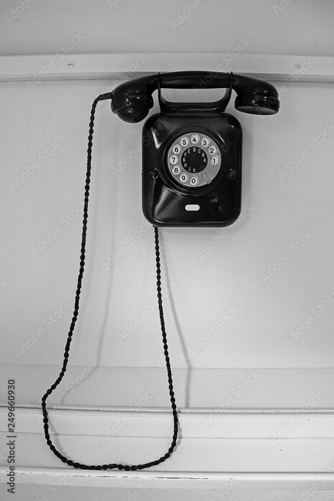 old-fashioned black telephone hanging on white wall old-fashioned black telephone hanging on white wall