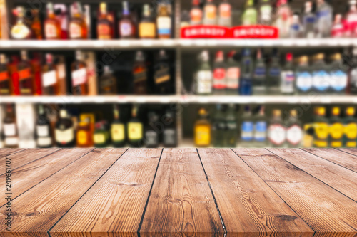 Wood table top and wine Liquor bottle on shelf blurred background photo