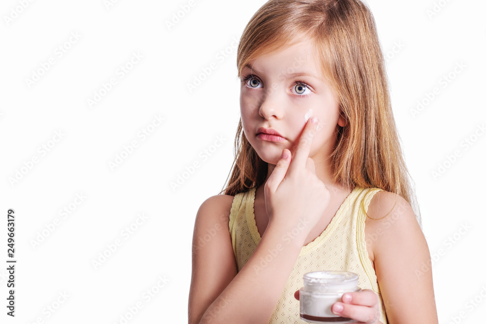 Portrait of little kid applying on facial cream isolated on white Portrait of little kid applying on facial cream isolated on white