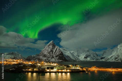 Aurora borealis dancing on mountain in fishing village at Reine and Sakrisoy  Lofoten  Norway Visiting the Lofoten Islands during winter time is a dream for all landscape photographers Christmas time