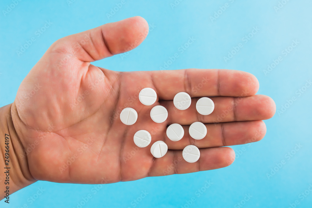 hand holding two pills over blue background