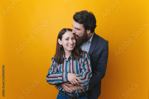 Cheerful excited glad happy with toothy beaming smile brunette attractive woman and with stylish hairdo bearded man, he is hugging her from the back © Vulp