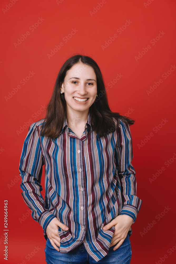 Portrait of happy young woman standing with hands in pockets against red background Portrait of happy young woman standing with hands in pockets against red background