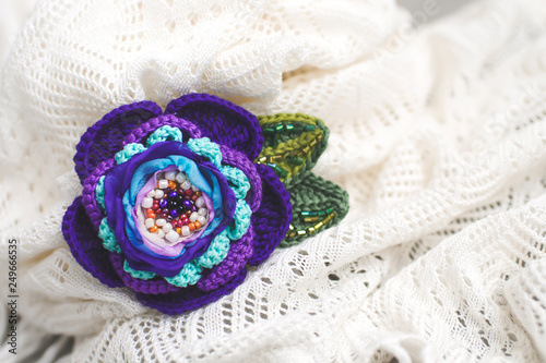 Women's hobby. Brooch in the form of beautiful violet color, on a white knitted openwork scarf.