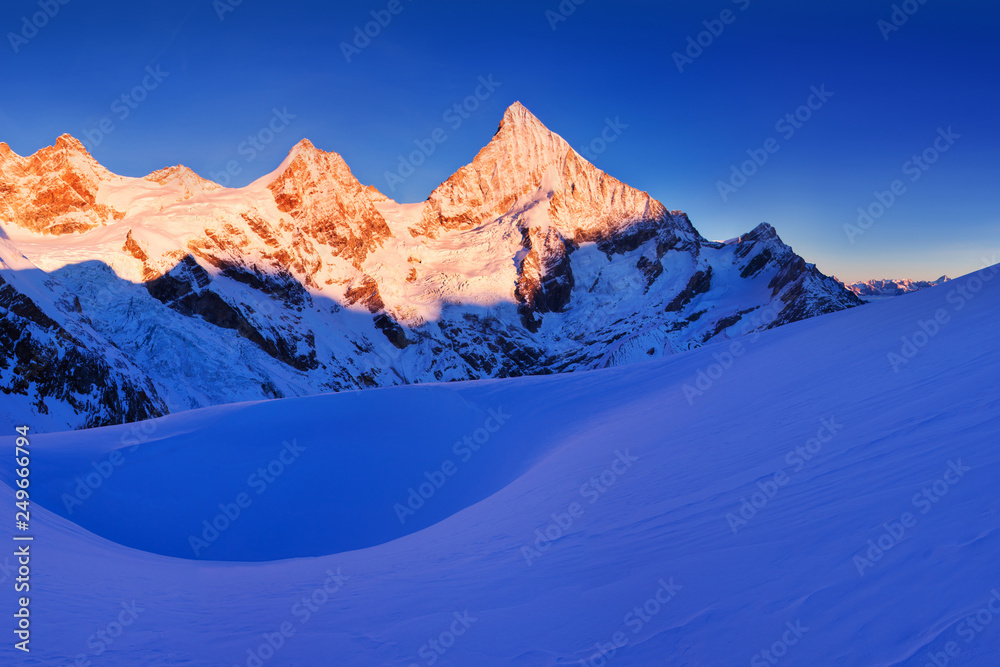 Fototapeta premium View of snow covered landscape with Dent Blanche mountains and Weisshorn mountain in the Swiss Alps near Zermatt. Panorama of the mountains in Switzerland. Beautiful morning with first snow. Christmas