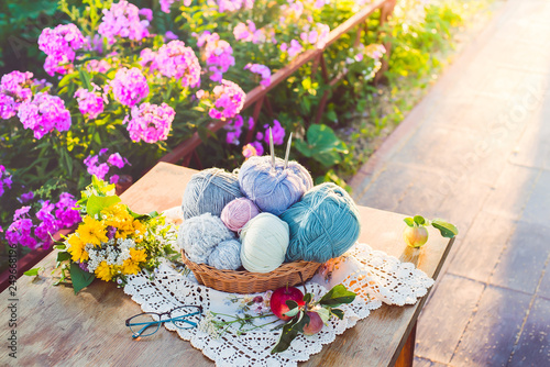 Women's hobby. Knitting and knitting needdles on the wood table in the garden on a Sunny summer day.	 photo