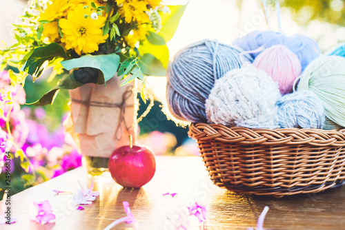 Women's hobby. Knitting and knitting needdles on the wood table in the garden on a Sunny summer day.	 photo