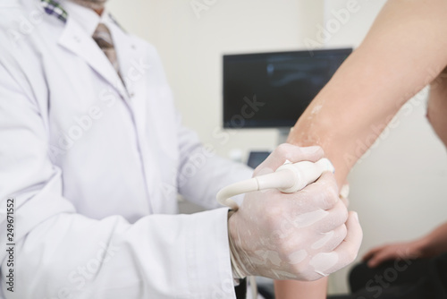 Doctor doing ultrasound diagnostics of elbow.