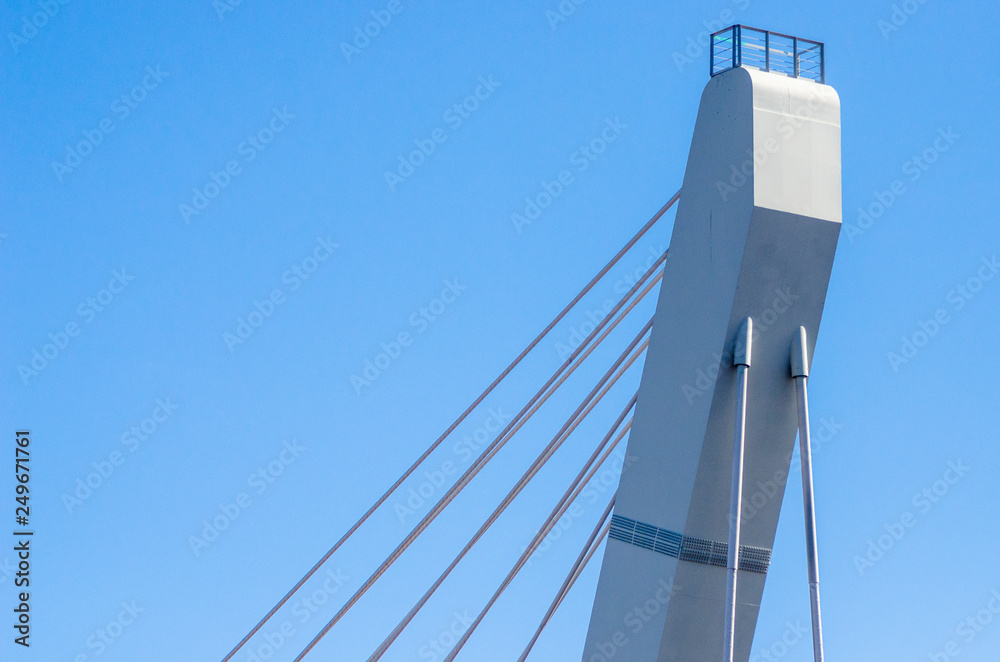 Obraz premium Cable-stayed bridge close-up against the blue sky. White bridge structure on a blue background. Neutral minimalistic background.