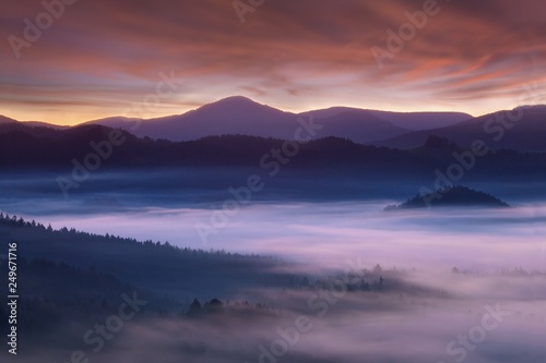 Beautiful summer or autumn sunrise above the forest valley of National park Bohemian Switzerland. Warm sunrise above the deep misty valley. Wonderful landscape background concept. Rays of lights  © Michal