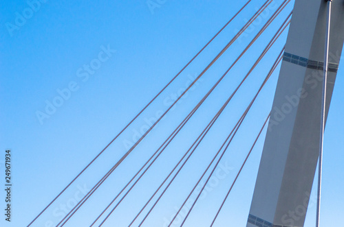 Cable-stayed bridge close-up against the blue sky. White bridge structure on a blue background. Neutral minimalistic background.