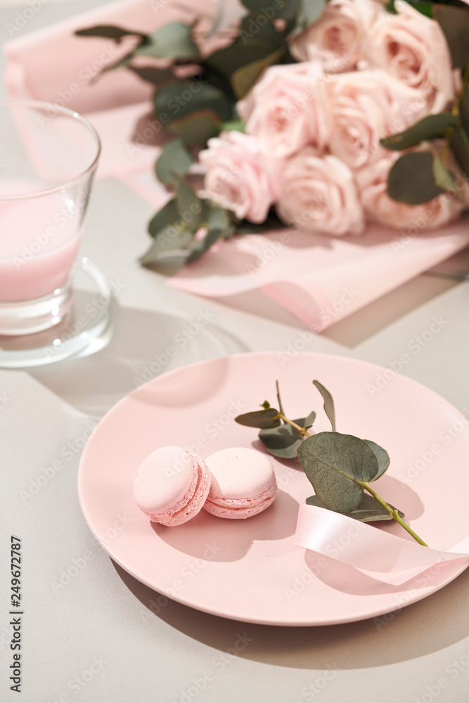 macaroons in pastel colors with bouquet of pink roses flowers on white background. Beautiful holiday background. copy space.