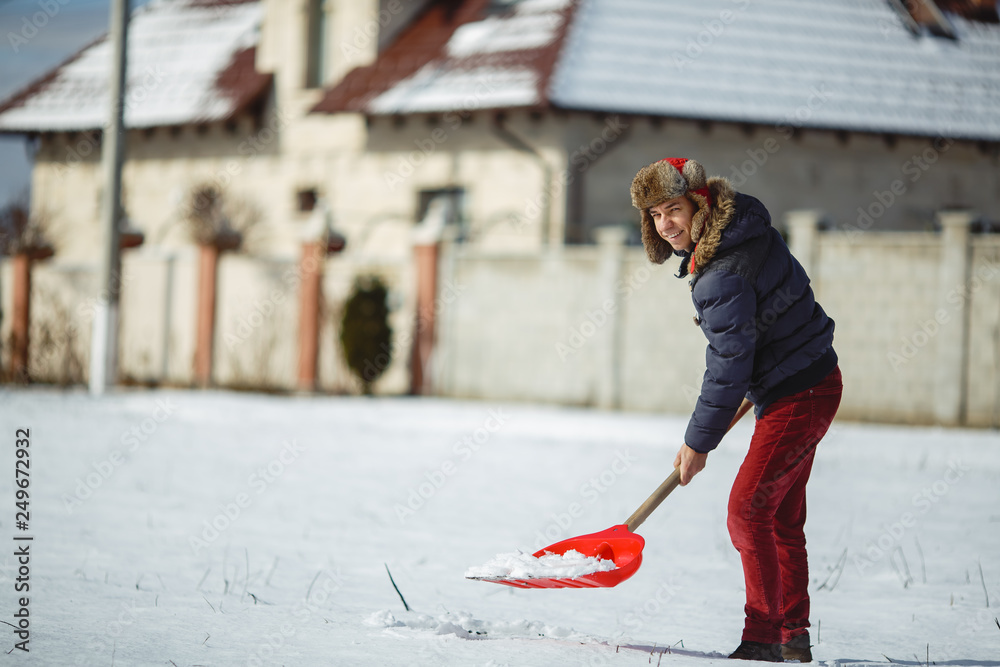 Happy man with a snow shovel in his hands against background snow Happy man with a snow shovel in his hands against background snow