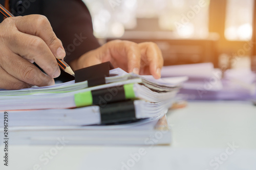 Accounting planning budget report file concept : Business woman offices check working for arranging documents unfinished stack of document papers with pen on busy office desk. Ideas for paperwork.