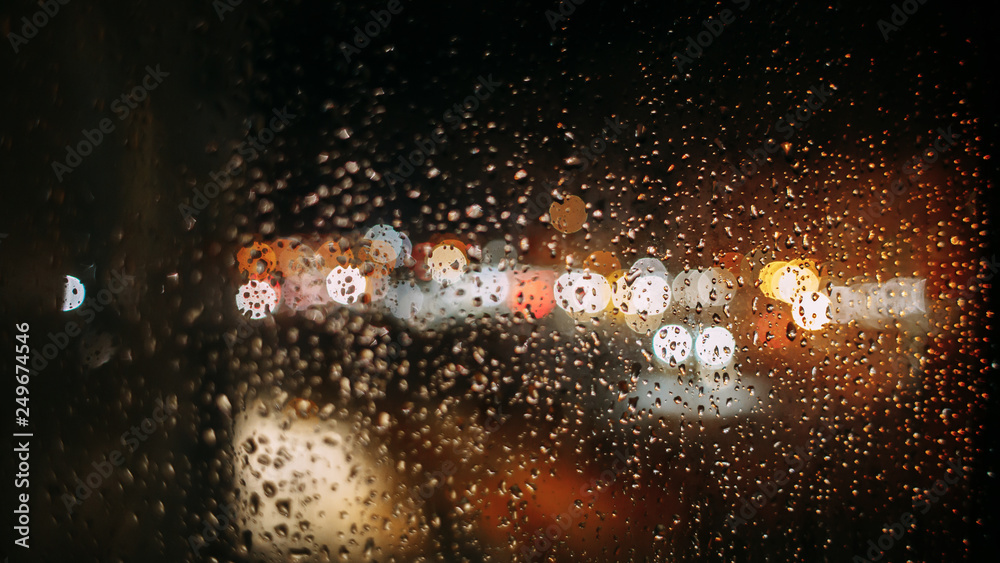 night city lights through the raindrops on the glass