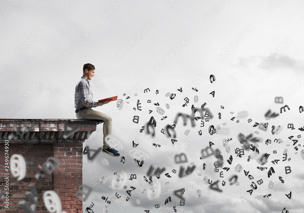 Man on roof edge reading book and symbols flying around Man on roof edge reading book and symbols flying around