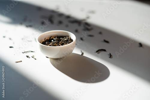 chinese tea in a  drinking bowl on white background with  scattered tea leaves on it in a shadow