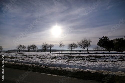 View from highway of winter landscape meadows and fields covered with layer of snow. Amazing natural environment with blue sky and sun. Beautiful landscape covered in snow in winter  seasons specific.