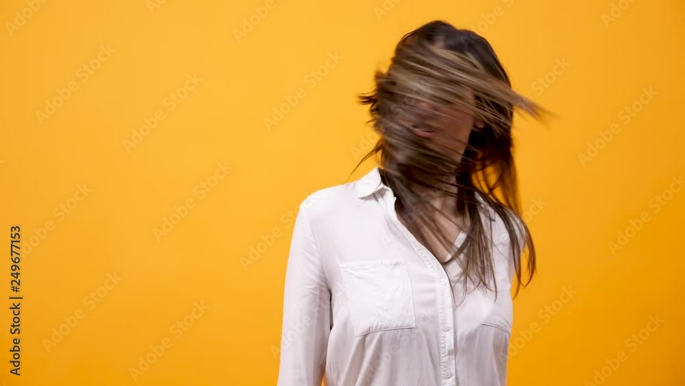Woman shaking her head on yellow background in slow motion Woman shaking her head on yellow background in slow motion