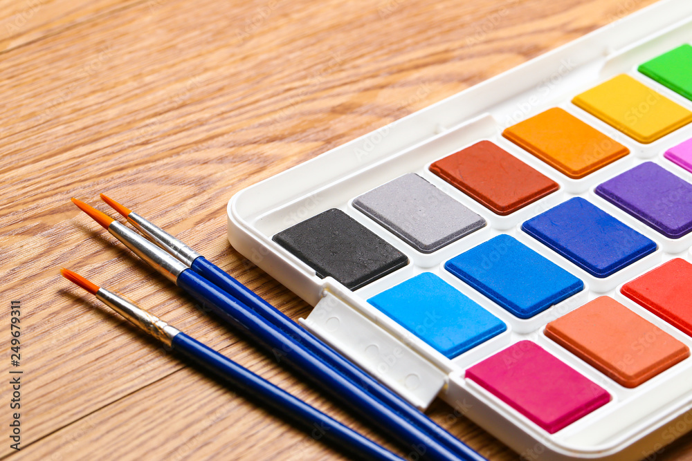 Set of solid watercolors and paintbrush on wooden table background Set of solid watercolors and paintbrush on wooden table background