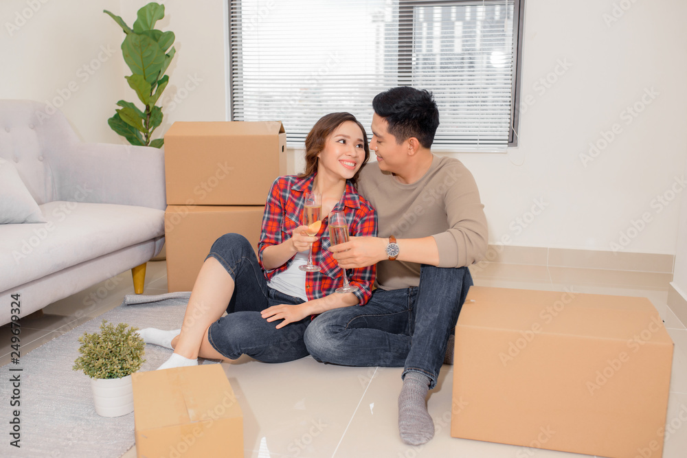 Close-up shot of joyful Asian couple clinking wine glasses together while sitting on floor of new apartment Close-up shot of joyful Asian couple clinking wine glasses together while sitting on floor of new apartment
